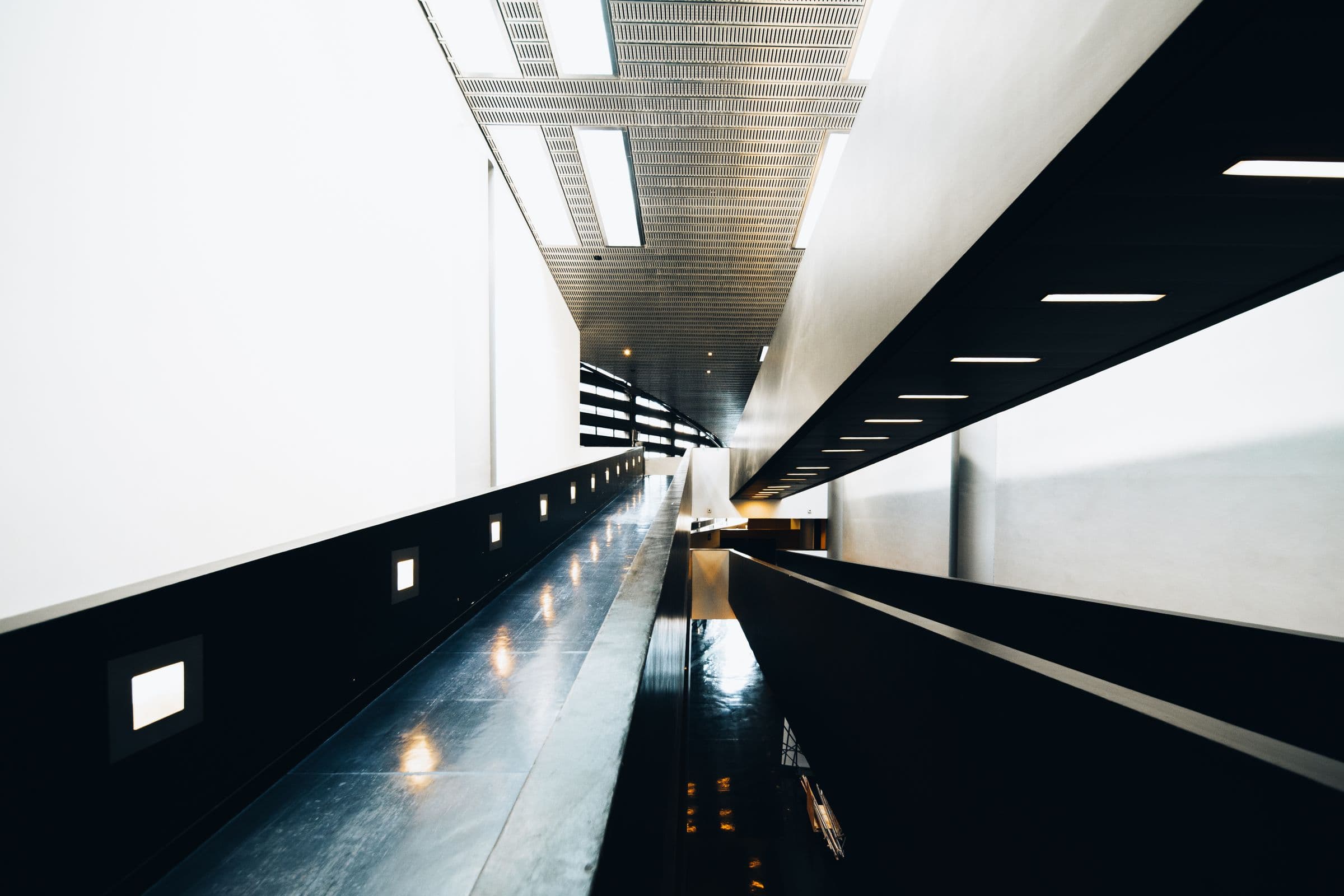 A long interior corridor receding into the dark, its ceiling picked out by warm light.