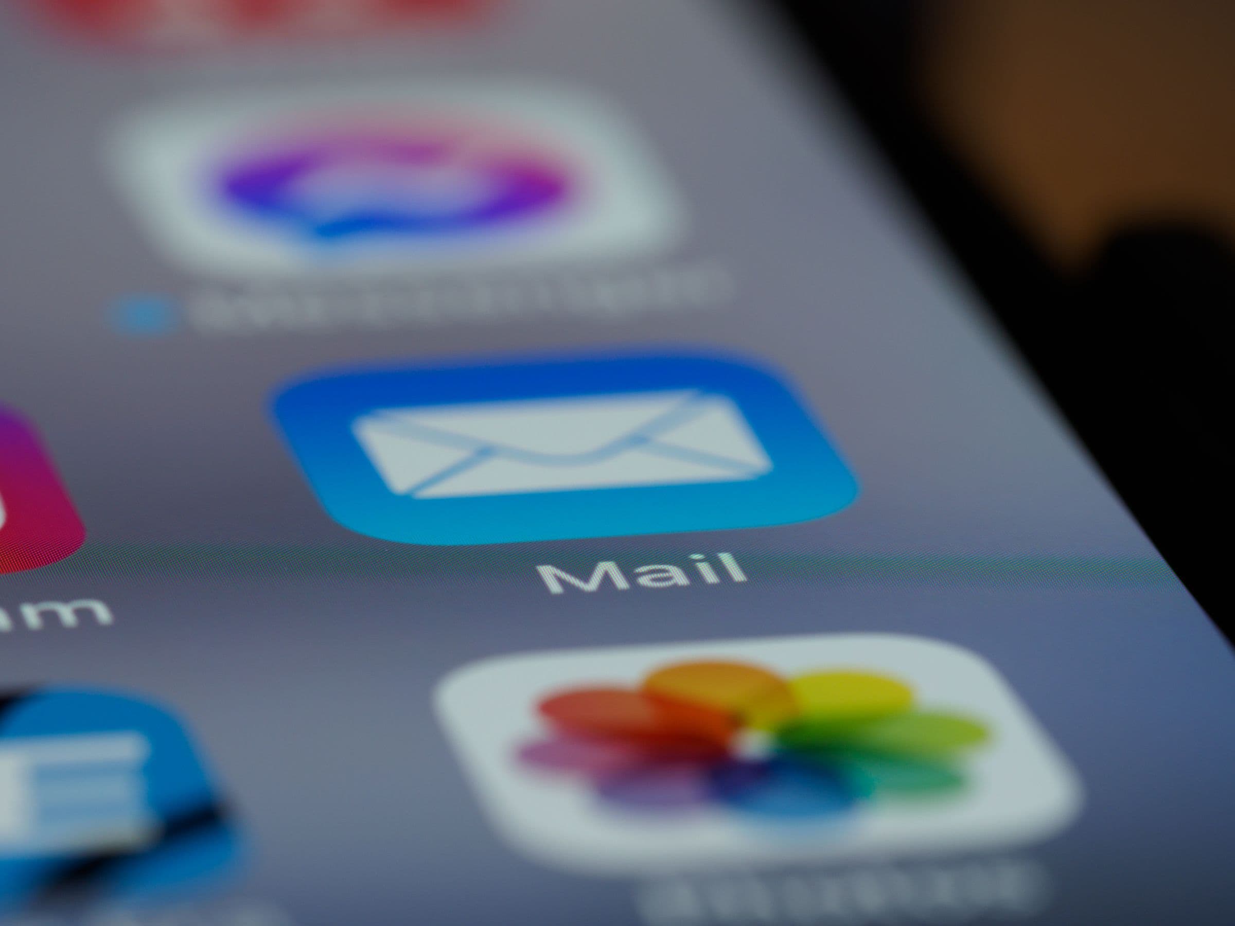 A macro close-up of a phone screen with the Mail app's envelope icon in sharp focus.