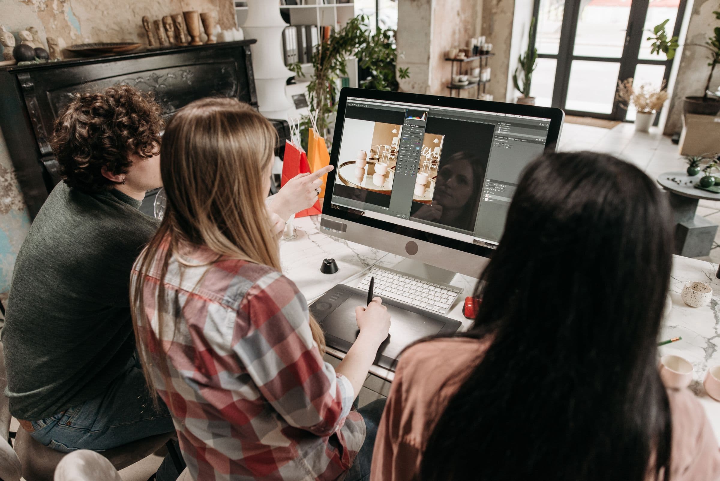 Three people gathered around one screen, reviewing work together.
