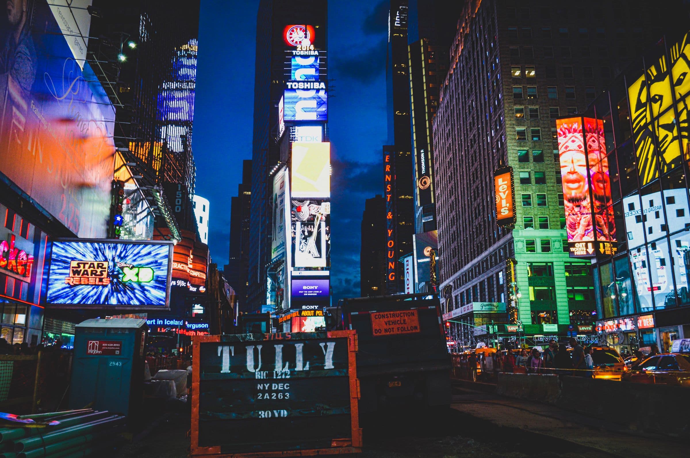 Times Square at night, its towers covered in lit digital billboards and display advertising.
