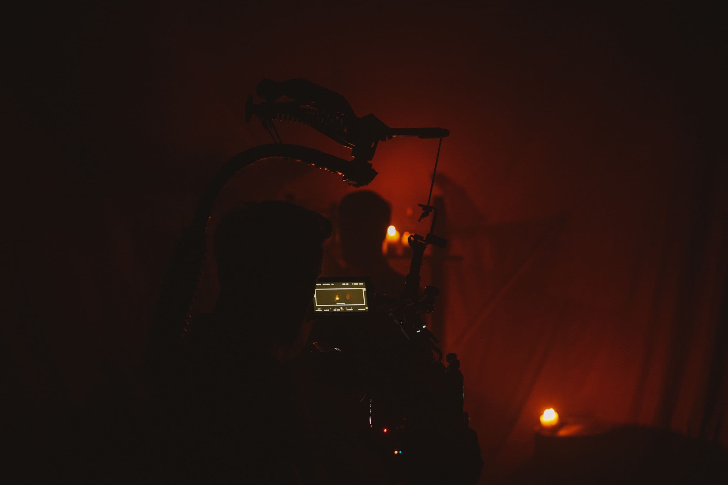 A camera rig silhouetted against warm haze on a lit set.